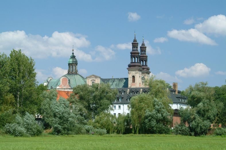 widok z łąk na barokowy klasztor z kopułą i dwiema wieżami
